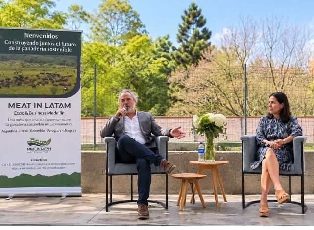 Panel de discusión al aire libre durante la cumbre de Meat in Latam. su fundador Julian David Urhán interviene con el micrófono desde su asiento junto a co fundadora Maritza Restrepo Diez y un pendón corporativo de la marca. Análisis de resiliencia y negocios registrado por Carlos DeMente y Doly Peñaranda para la Revista Club PRO.